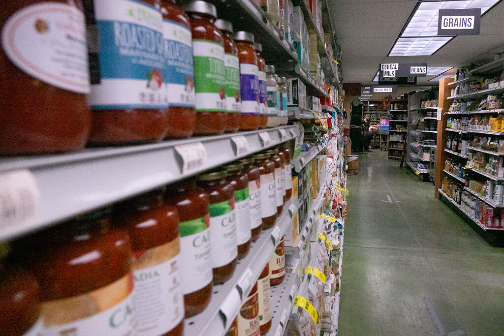 A shelf full of specialty tomato sauce is ready for purchase